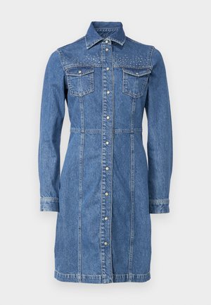 Rochie din denim cu maneci lungi, buzunare frontale și accente cu nituțe argintii pe umeri. Prezintă un sistem de închidere cu butoane pe față.