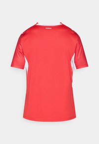 Κόκκινο αθλητικό κοντομάνικο τζέρσεϊ με λευκές λεπτομέρειες. Διαθέτει στρογγυλή λαιμόκοψη και υφασμάτινες πλευρικές πάνελ. Λογότυπο "suisse" στην άνω πλάτη.