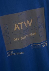 Blaues T-Shirt mit grauem Grafikdesign und dem Text "ATW OFF DUTY GEAR" sowie verschiedenen technischen Details in Gold und Blau.