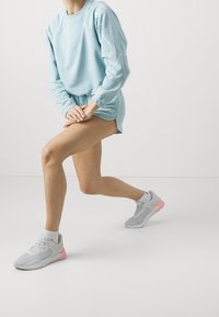 Světle modré mikina s bílým obrysem, v kombinaci se strukturovanými světle modrými šortkami. Šedé tenisky s růžovými akcenty a bílé ponožky.