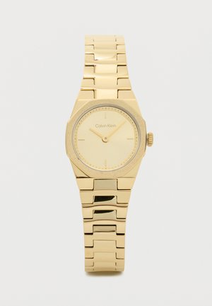 Montre-bracelet dorée au ton or avec un cadran octogonal, un cadran minimaliste et des accents texturés. Design de bracelet à maillons pour un ajustement sécurisé. Nom de la marque visible.