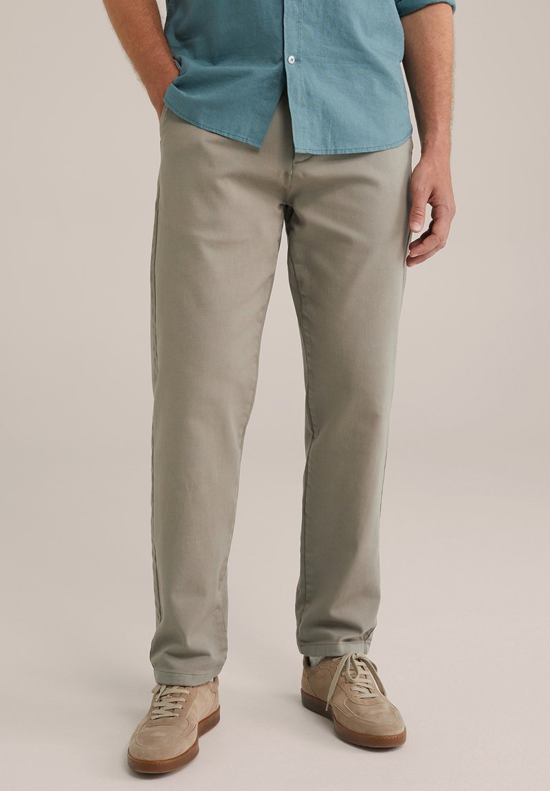 Pantalones de algodón gris claro con corte recto, que cuentan con bolsillos laterales, combinados con zapatos de ante beige y una camisa de botones azul.