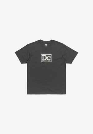 Dunkelgraues Baumwoll-T-Shirt mit einem auffälligen weißen "DC"-Logo und dem Text "DC SHOES 1994" innerhalb eines rechteckigen Rahmens. Kurze Ärmel, Rundhalsausschnitt.