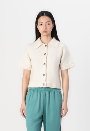 Cardigan en tricot à manches courtes en crème avec un col et une fermeture à boutons, featuring des poignets et une taille côtelés.