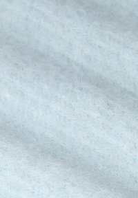 Nahaufnahme von weichen, hellblauen, flauschigen Stofffasern mit einer zarten, luftigen Textur.