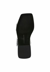 Schwarze Sohle mit strukturiertem Muster und breitem Absatz. Silberne metallische Akzente an der Seite. Das Etikett trägt die Aufschrift "Steve Madden." Flaches Grunddesign.
