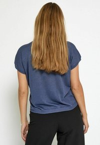 Plava majica kratkih rukava od mekanog materijala s opuštenim krojem, koja ima suptilnu teksturu i rub koji pada ispod struka.