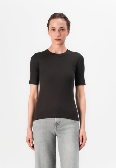 Sort ribbenstrikket kortærmet t-shirt med rund halsudskæring. Blød tekstur, tætsiddende design, parret med lysegrå lige ben jeans.