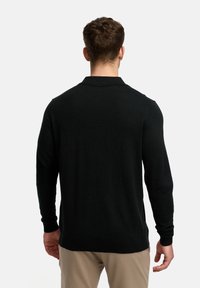 Schwarzer Strickpullover mit langen Ärmeln und umgeschlagenem Kragen, mit einer glatten Textur und enganliegendem Design, von hinten betrachtet.