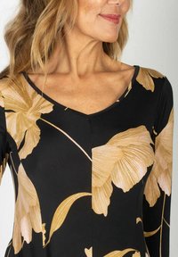 Czarna sukienka z złotymi kwiatowymi wzorami; posiada dekolt w serek, długie rękawy, gładką fakturę oraz dopasowany krój podkreślający dekolt.