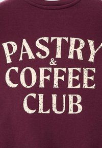 Tessuto borgogna con testo bianco in grassetto e rovinato che legge "PASTRY & COFFEE CLUB" centrato sulla superficie.