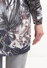 Camicia a maniche lunghe con stampa floreale in tonalità di viola e grigio, con polsini con bottoni e orlo dritto.