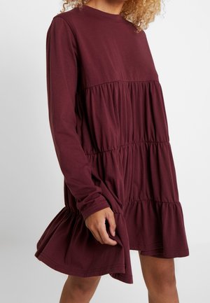 Bordeauxrode jurk met lange mouwen, een gelaagd ontwerp, een geplooide taille en een wijd uitlopende zoom. Gemaakt van zachte, lichtgewicht stof.