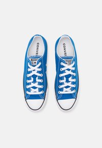 Sneakers in tela blu con lacci bianchi, punta in gomma bianca e bordi neri. Presentano il logo Converse All Star sulla linguetta.