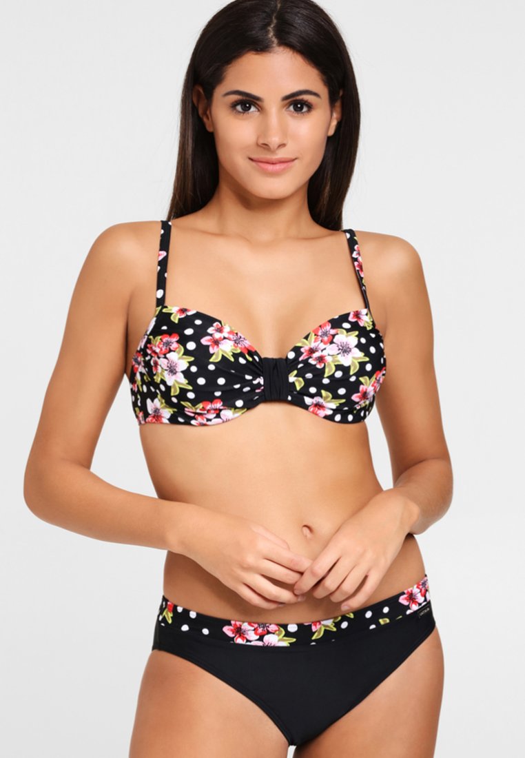 Zwarte bikini top met een bloemenpatroon en witte stippen, voorzien van een middelste strik. Bijpassende zwarte bikini broekjes met bloemen- en stipaccenten.