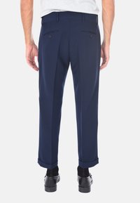Pantaloni tailored blu navy con texture liscia, due tasche posteriori e orli arrotolati, progettati per un aspetto formale.