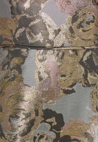 Mönstrad tyg med metalliskt guld, rosa och svarta blommönster på en grå bakgrund, med en slät textur och lätt lyster.