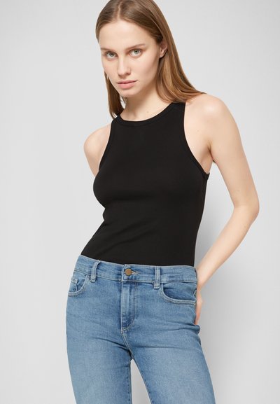 Top preto de alças com um decote alto, feito de um tecido elástico. Combinado com jeans justos de tom azul claro, com bolsos frontais e fecho de botão.