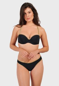 Svart bikini-set med en strapless topp med guldaccenter och formade kupor, i kombination med låghängande bottnar, båda tillverkade av ett glatt material.