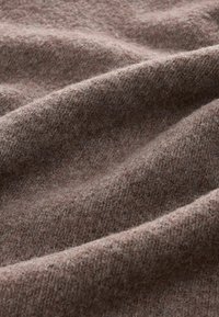 Wollen stof in een zachte bruine kleur met een zachte, gestructureerde oppervlakte, met subtiele plooien en een warme, gezellige uitstraling.