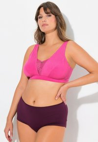 Bralette de algodón suave rosa con detalles de encaje, con un diseño de escote en V. Combinado con ropa interior de algodón morado oscuro de cintura alta.