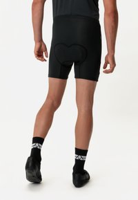 Pantaloni corti da ciclismo neri realizzati in materiale elastico, con dettagli in imbottitura a forma di cuore, caratterizzati da un alto elastico in vita per supporto.