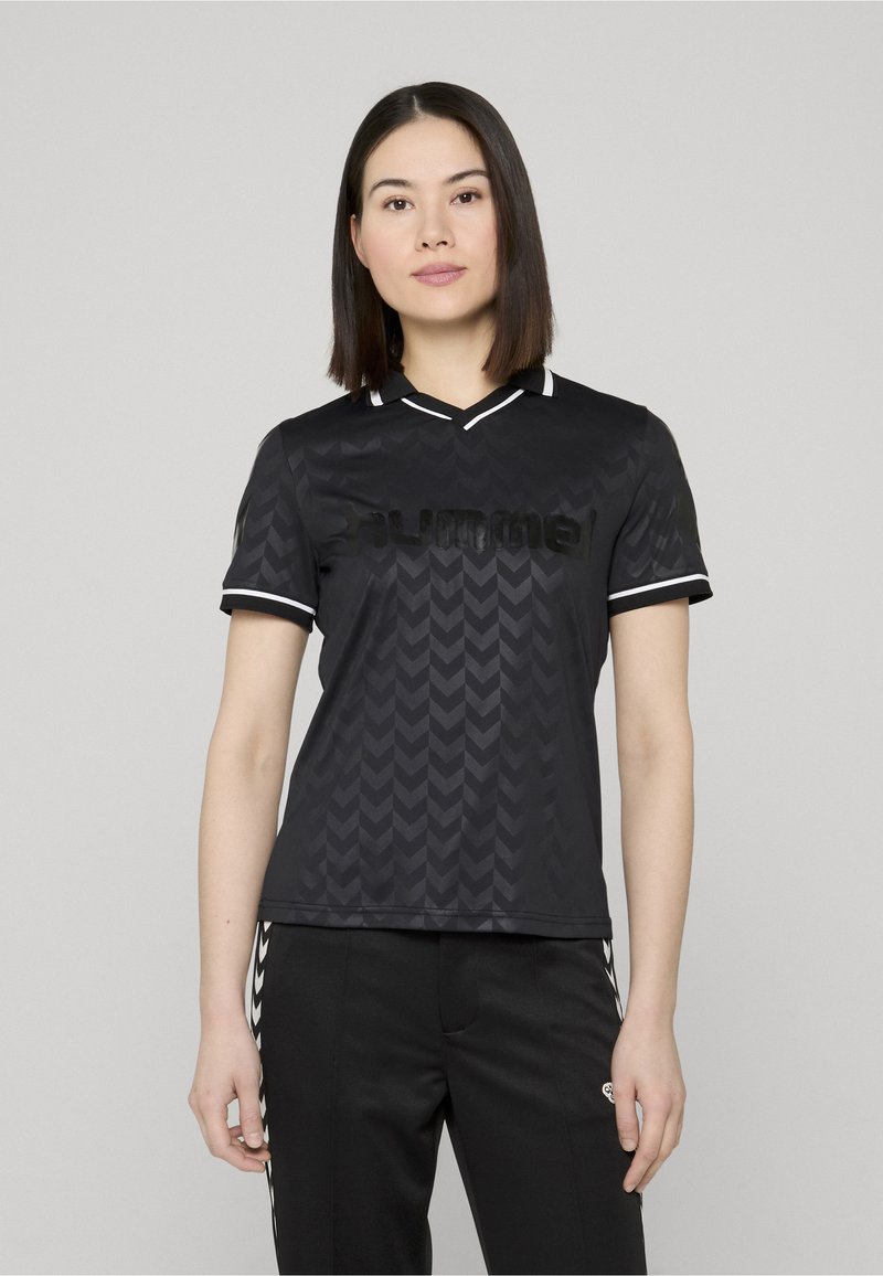 Maillot de sport noir avec un motif en chevron, manches courtes, col en V avec des accents blancs, et un logo imprimé sur la poitrine.