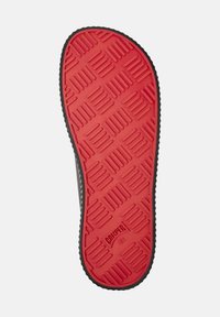 Suela de zapato con una parte inferior de goma roja que presenta un patrón texturizado y un borde negro. El texto grabado dice "CAMPER 42."