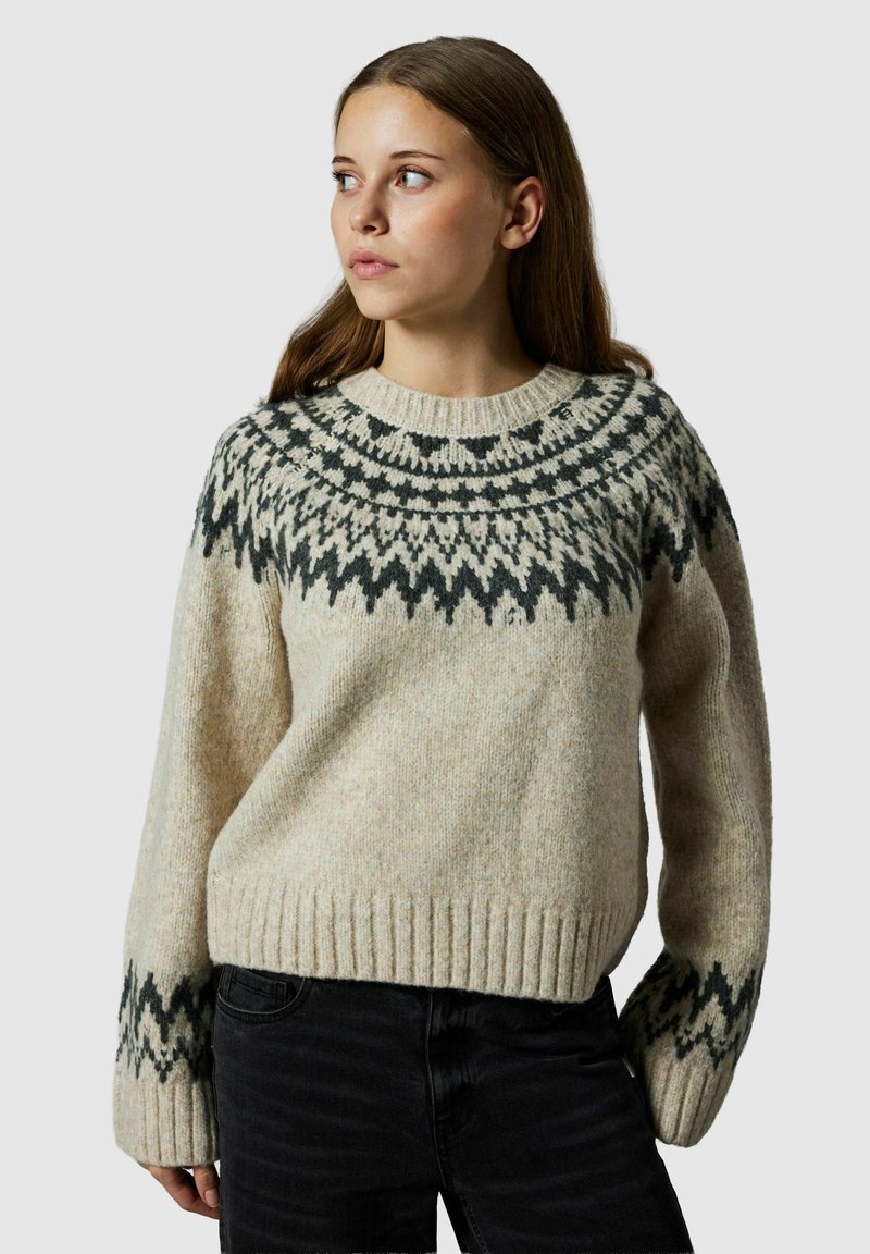 Beżowy sweter wełniany z okrągłym dekoltem, zdobiony ciemnozielonymi wzorami geometrycznymi wokół karczku oraz prążkowanymi mankietami i dołem.