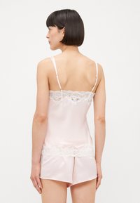 Rózsaszín selyem camisole csipkebordűrrel és állítható pántokkal, laza szabással. Illik hozzá egy hasonló selyem sort csipke díszítéssel.