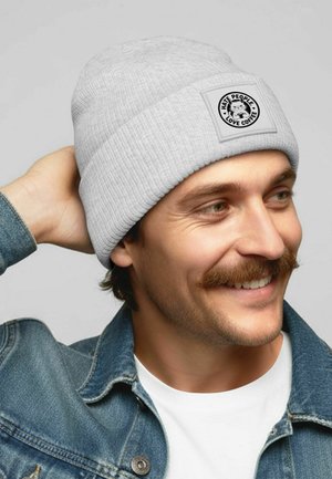 Gray ribbed beanie with a square patch featuring a coffee-themed graphic and text, worn by a person against a neutral background.