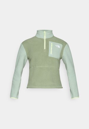 Pulover od flisa u svijetlozelenoj boji s ovratnikom na zip, koji ima džep na prsima i kontrastne detalje na rukavima i rubovima u sličnoj nijansi.