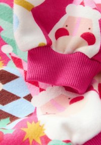 Gemusterter Stoff in Rosa- und Pastellfarben mit Santa-Illustrationen, strukturiert mit gerippten Bündchen und verspielten geometrischen Designs.