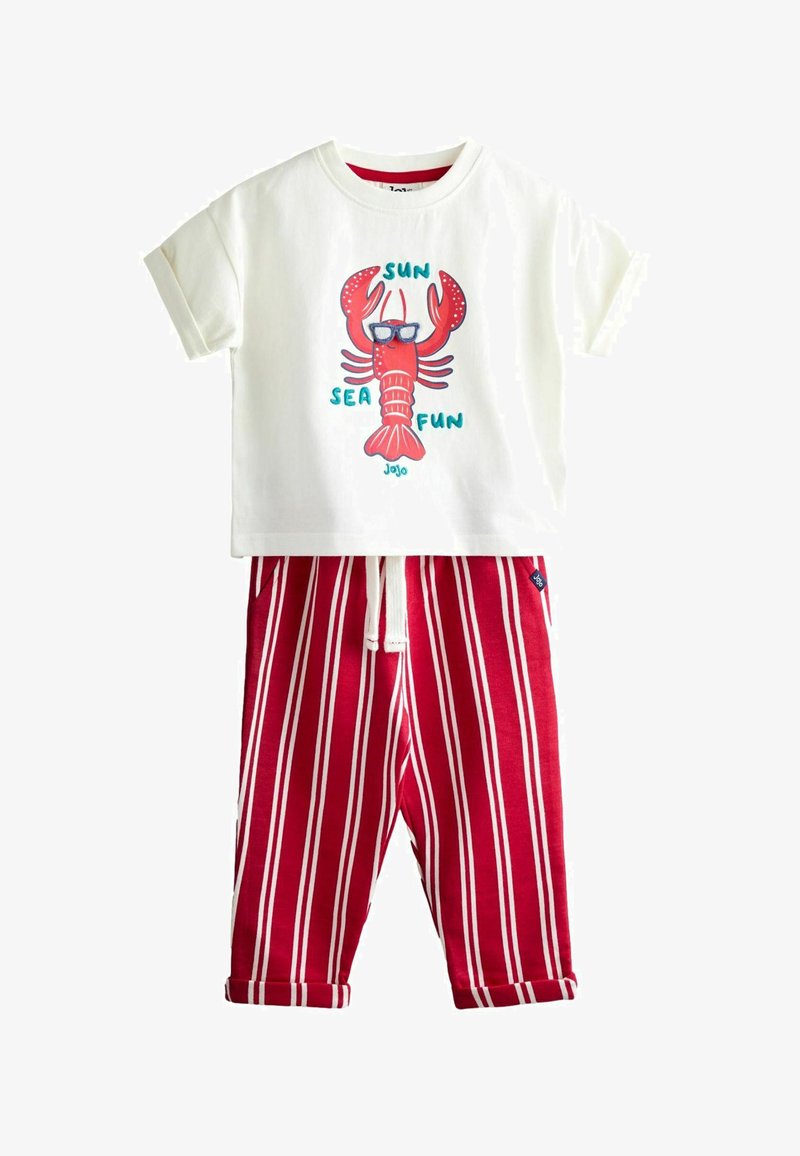 Valge lühikeste varrukatega särk, millel on punase prillidega homaar ja tekst "Päike, meri, lõbu", sobitatud punase-valgete triipudega pükstega, millel on nöörvöö.