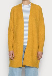 Cardigan giallo senape realizzato in materiale a maglia testurizzato, con apertura frontale, maniche lunghe e due tasche a toppa frontali.