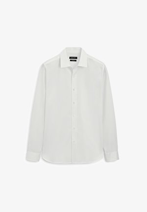 Biała koszula męska z długim rękawem, zapinana na guziki, z ostrym kołnierzykiem i mankietami zapinanymi na pojedynczy guzik, ułożona na płasko na białym tle.