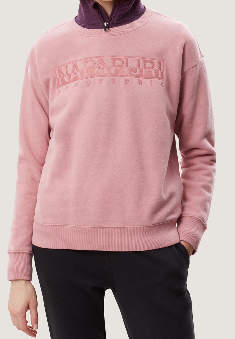 Felpa rosa con un design del logo testurizzato sulla parte anteriore, polsini e orlo a coste. Indossata sopra un top scuro, con una vestibilità comoda.