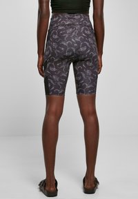 Shorts da bici neri a vita alta con un motivo floreale bianco, texture liscia e pannelli laterali per un dettaglio di design aggiunto.