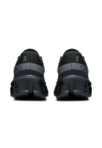 Schwarze Sportschuhe mit einem strukturierten Obermaterial, grauen Akzenten und einem auffälligen Sohlen-Design. Markenlogo sichtbar an der Ferse und an der Seite.
