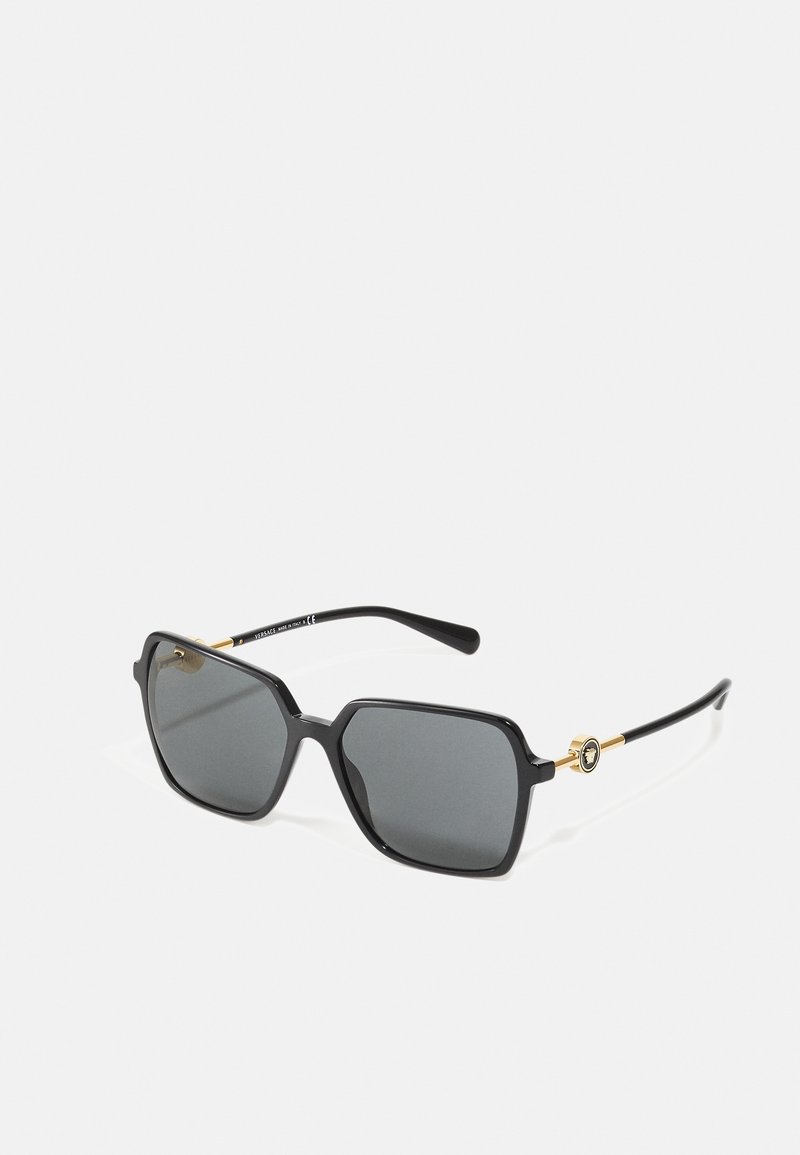 Óculos de sol retangulares pretos com lentes cinzas, apresentando uma armação de plástico elegante e um detalhe dourado nas hastes. Design simples, sem padrões visíveis.