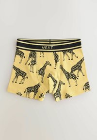 Gule boxershorts med print af sorte giraffer, med en sort elastisk talje, der viser mærkenavnet "NEXT." Blødt bomuldsstof.