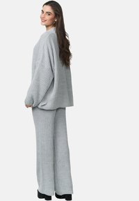Set di maglione a coste grigio e pantaloni a gamba larga, caratterizzato da una vestibilità ampia e un tessuto testurizzato. L'outfit presenta maniche lunghe e una silhouette rilassata.