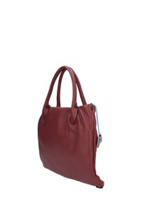 Borsa a tracolla in pelle rossa con doppi manici, tessitura morbida, chiusura a zip con linguetta di tiraggio blu. Presenta bordi arrotondati e una forma strutturata.