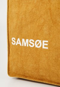 Gul stoffpose med "SAMØE"-tekst i hvitt, med en teksturert overflate og sømte kanter for holdbarhet.