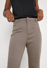 Bruin en tan geblokte broek met een aansluitend ontwerp, riemlussen, zijzakken en een gladde stofstructuur.