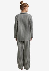 Black and white checkered pajama set with a long-sleeve button-up top and loose-fitting pants, featuring a soft fabric texture.