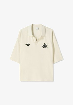 Polo crème à manches courtes, avec des logos noirs sur la poitrine gauche et le col, et un design décontracté.