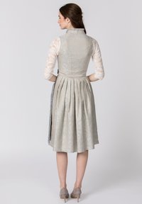 Light blue and gold patterned dirndl with pleated skirt, lace blouse, and a fitted bodice. Features a side ribbon tie and ankle-length design.