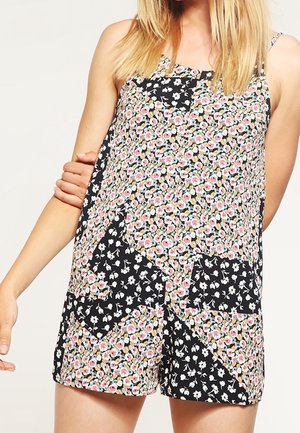 Mono tipo prensado con estampado floral en negro, que presenta pequeñas flores en rosa, amarillo y blanco. Incluye dos bolsillos en la parte delantera y tirantes ajustables.