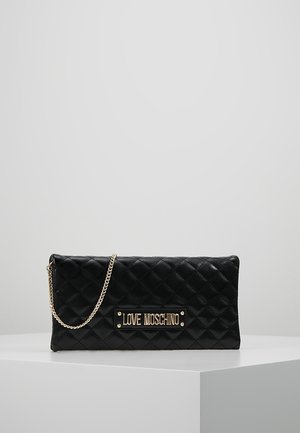 Pochette matelassée noire avec bandoulière chaîne dorée et plaque logo dorée "LOVE MOSCHINO" à l'avant, exposée sur un socle blanc.